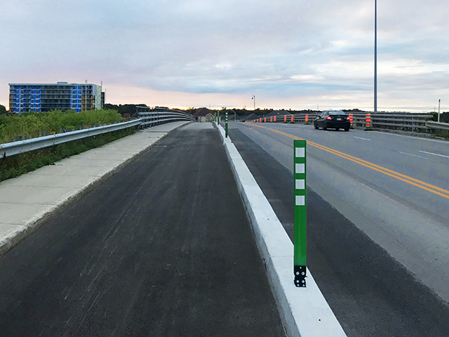 Piste cyclable sur un viaduc protégée muret de béton et poteaux bollards flexibles