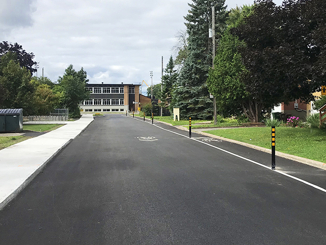 Piste cyclable protégée avec bollards flexibles près d'une école